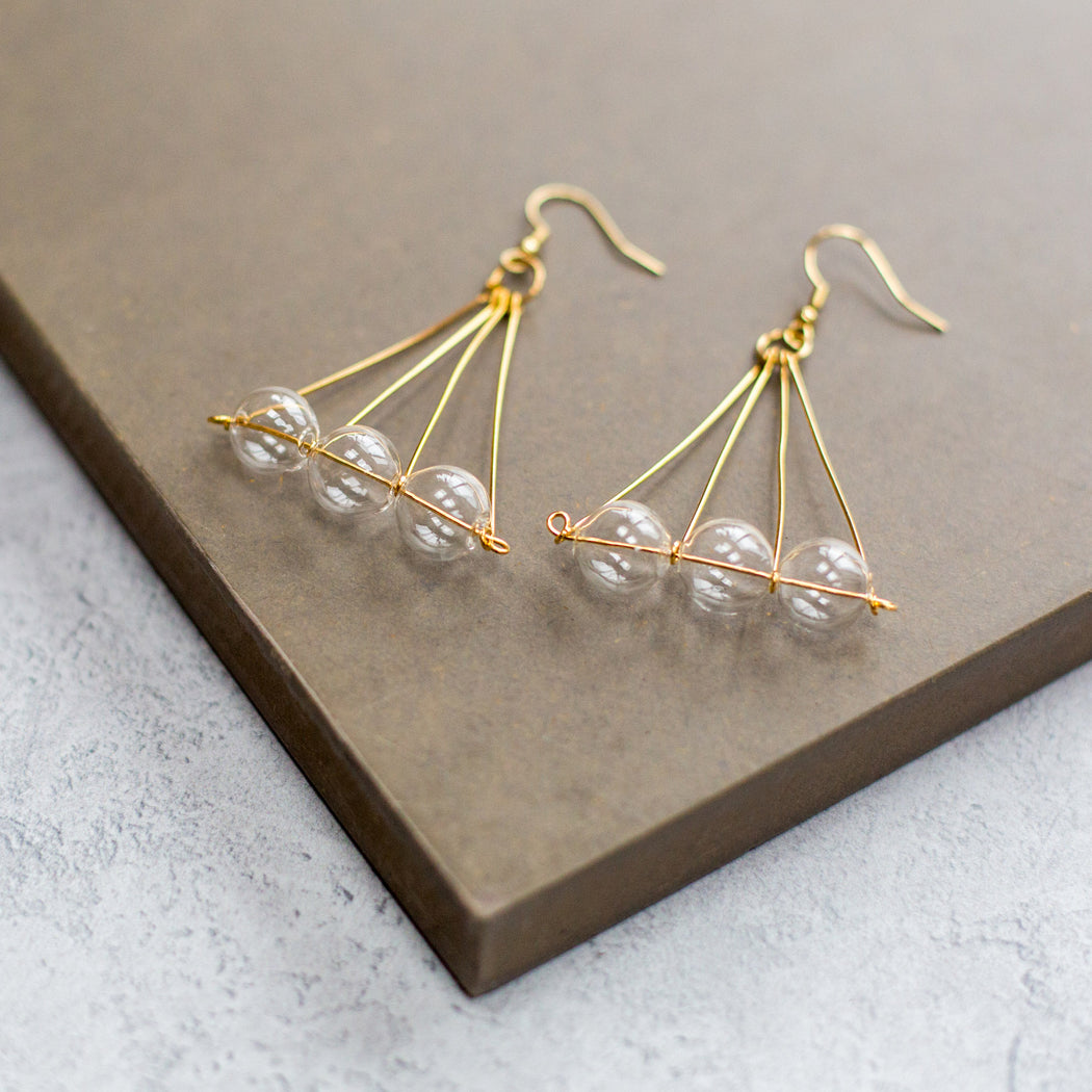Brass earrings with three clear glass beads in a pyramid shape by  a UK black owned jewlery brand 